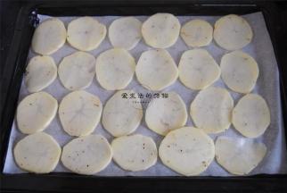 烤盘里铺上油纸，将土豆片整齐的码入烤盘里。