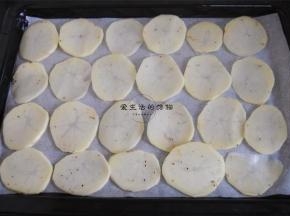 烤盘里铺上油纸，将土豆片整齐的码入烤盘里。