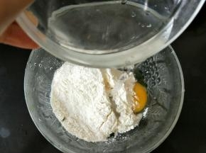 然后加入50克面粉，再倒入80克清水，一边用筷子搅拌均匀。