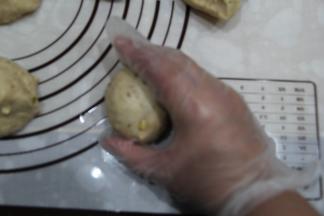 右手如图握住一个面团，反C空心掌，握住逆时针滚圆。揉圆8个面团。