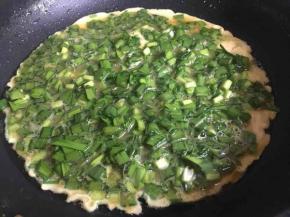 锅中倒入少许油，油八成热倒入韭菜蛋液，再用筷子调整均匀，煎制过程中偶尔前后晃动煎锅，使蛋饼受热均匀且不粘锅；