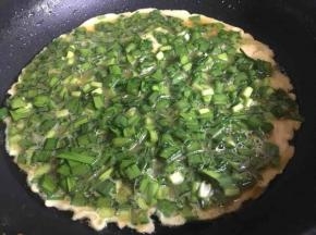锅中倒入少许油，油八成热倒入韭菜蛋液，再用筷子调整均匀，煎制过程中偶尔前后晃动煎锅，使蛋饼受热均匀且不粘锅；