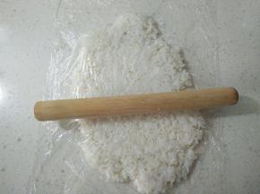 将桌面先铺一层保鲜膜，放上米饭，上面再铺一层，用擀面杖擀成薄片。