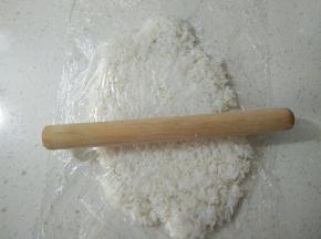 将桌面先铺一层保鲜膜，放上米饭，上面再铺一层，用擀面杖擀成薄片。