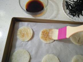 把米饼翻面，用刷子蘸少许酱汁，刷在米饼上。