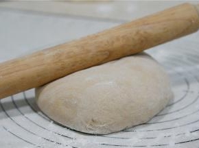 用擀面棒将面团擀至方长薄面皮状。