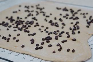 面皮擀好，在表面配入红豆粒及玫瑰花碎末。