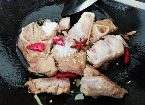 热锅下油，把蒜瓣爆香，倒入洗净泡出血水的肉骨翻炒，分别倒入料酒，生抽，白砂糖，盐调味，接着放入辣椒，八角炒出香味。