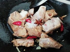 热锅下油，把蒜瓣爆香，倒入洗净泡出血水的肉骨翻炒，分别倒入料酒，生抽，白砂糖，盐调味，接着放入辣椒，八角炒出香味。