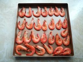 浸泡入味的基围虾捞出来沥一下水分，放到烤盘里，间隔出一些空间