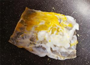 磕入鸡蛋在面皮上，用锅铲把蛋黄戳破，均匀涂抹在面片上。