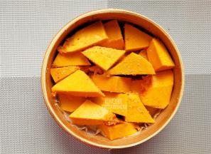 南瓜去皮去籽，切块裹上少许米粉，铺入容器底部。