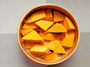 南瓜去皮去籽，切块裹上少许米粉，铺入容器底部。