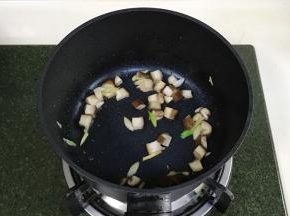 开火，锅中加入少许食用油，加入蘑菇丁炒至变色，加葱姜翻炒片刻。