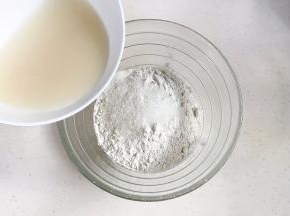 往大碗内加入中筋面粉、细砂糖和玉米油，牛奶中加入酵母粉，用筷子拌匀后倒入。