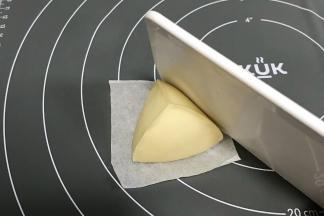 用刮板辅助倾斜按压，手和刮板一起成角度挤压，整成三角形。