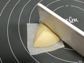用刮板辅助倾斜按压，手和刮板一起成角度挤压，整成三角形。