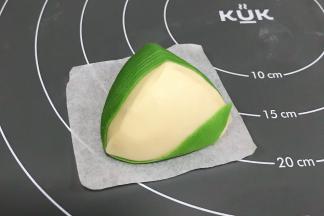 把粽叶从前面往底面绕到顶部上，接着继续往下面。