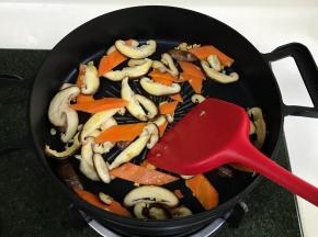 加入胡萝卜约炒1分钟变色，接着倒入蘑菇片炒软。