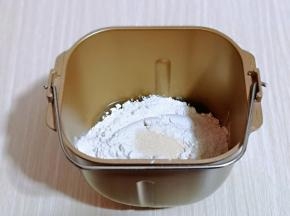 将称重的中筋面粉和白糖，两个鸡蛋打散放入面包桶里，倒入花生油和酵母，启动面包机的和面模式开始和面。