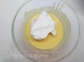 将1/3的蛋白霜加入到蛋黄糊中，用橡皮刮刀翻拌均匀