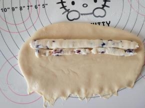 8、翻面，将底边压薄。挤入奶酪馅，从上卷起，收紧封口。