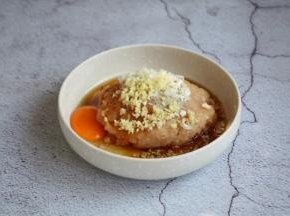 将鸡肉泥放在一个较大的容器里，放入1个鸡蛋、少许的白胡椒粉、1勺的料酒、淀粉2勺、1小勺的生抽、葱花姜末各5g。

