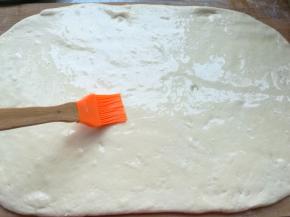 案板撒上面粉，发酵好的面团取出来揉匀，擀成长方形大面片，均匀地撒上适量的食用盐，再薄薄的刷上一层食用油。