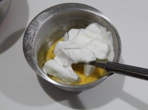 蛋白霜取1/3入蛋黄糊中，用刮刀从中心点切入从底部往盆边翻起到中心点，翻拌均匀。