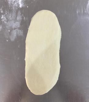 松弛好的面团擀成长条，椭圆形。