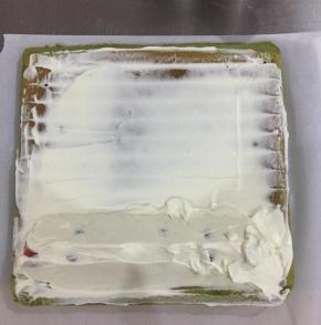 把打发好的淡奶油抹在蛋糕上，放上草莓，卷好后放入冰箱定型。