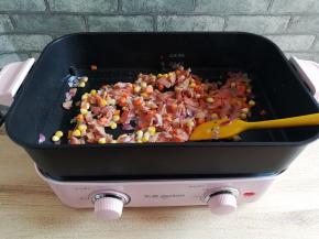 培根煎到微微焦黄，加入玉米粒，胡萝卜丁和洋葱碎转大火翻炒熟透