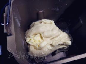 将除黄油外,把主面团的其它原材料按照底层液体，中层粉类，上层糖、盐和酵母的顺序放入面包中，启动一个揉面程序，揉至能拉出比较厚的膜后加入黄油。