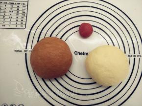 发酵好的面团发酵好的面团用擀面杖排气，先分出16g（加红曲粉，做爱心），剩下的平均分成两份，一份加入可可粉。分别将面团揉匀，这样子我们就得到了三个颜色的面团。