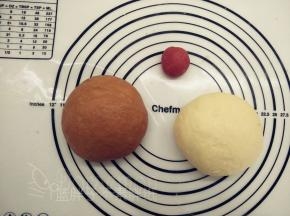 发酵好的面团发酵好的面团用擀面杖排气，先分出16g（加红曲粉，做爱心），剩下的平均分成两份，一份加入可可粉。分别将面团揉匀，这样子我们就得到了三个颜色的面团。