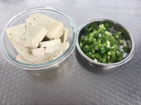 将豆腐切成半厘米厚的片，葱切碎备用。