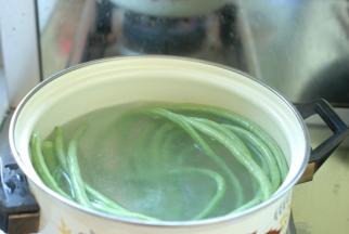 先把长豆角择洗干净，用盐水浸泡5分钟后，捞出来再冲洗两遍，豆角就清洗干净了。然后把锅里放入适量清水烧开，水开后加入1勺盐，1勺食用油，把把清洗干净的长豆角放入锅里，水开后大约煮3¬¬—5分钟，直到豆角煮软。