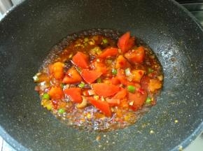 然后加入葱花、姜末，再加入一半的蒜末炒出香味。把洗净切好块的西红柿块放进锅里，翻炒出西红柿汤汁。