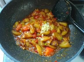 把调好的料汁倒进去，翻炒均匀，然后把茄子放进锅里，加入1勺盐，还有剩下的另一半蒜末，炒香。