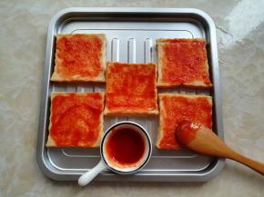 把迷你吐司片放到烤盘里，刷一层番茄酱