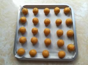 烤盘里垫一张油纸，把饼干面团按照10克每个分成24个，揉圆一下