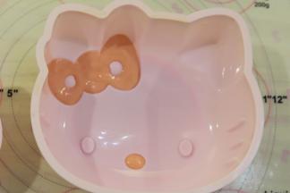 准备一个KT硅胶蛋糕模，红色蛋糕糊填充在KT的蝴蝶结和鼻子上。