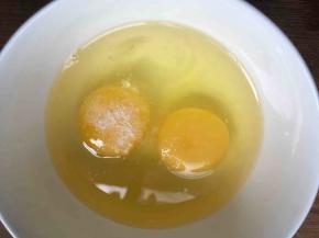 碗中磕入2枚鸡蛋，倒入少许盐，搅打均匀；