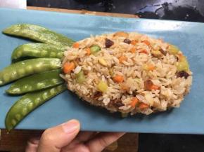 将米饭整理成菠萝上窄下宽的形状，荷兰豆摆成菠萝叶子的形状；