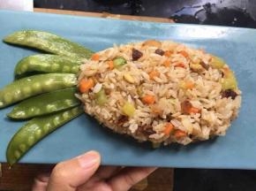 将米饭整理成菠萝上窄下宽的形状，荷兰豆摆成菠萝叶子的形状；