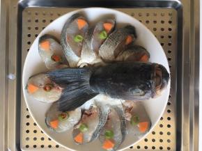 盘子底铺上葱姜丝，腌制好之后把鱼摆在盘子中，放上胡萝卜小米椒香葱装饰一下。