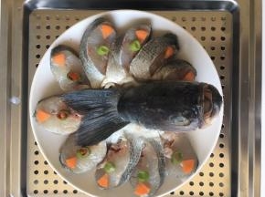 盘子底铺上葱姜丝，腌制好之后把鱼摆在盘子中，放上胡萝卜小米椒香葱装饰一下。