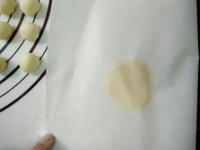 取一个酥皮放在油纸½处，盖上油纸，上面放上刮板用手左右按压，成为圆片。