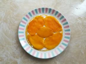 准备一个干净的盘子，放上一张千层饼皮，抹上适量的淡奶油，再放上芒果片，上面再铺一层淡奶油