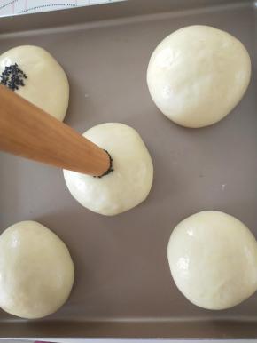 12、发酵结束后面团表面涂全蛋液，用擀面杖一头沾水，再蘸芝麻，轻轻压在面团中间。